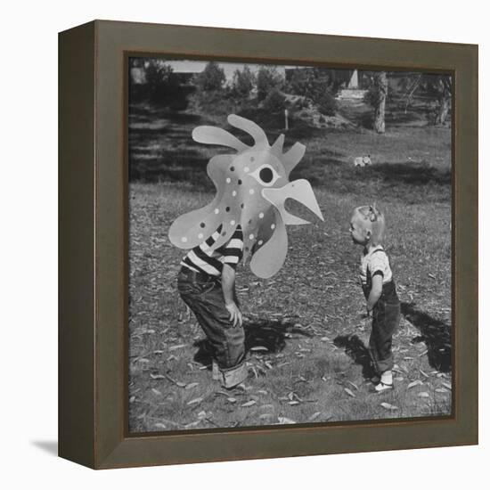 Curious Girl Looking at a Toy Chicken Head Toy by Charles Eames-Allan Grant-Framed Premier Image Canvas