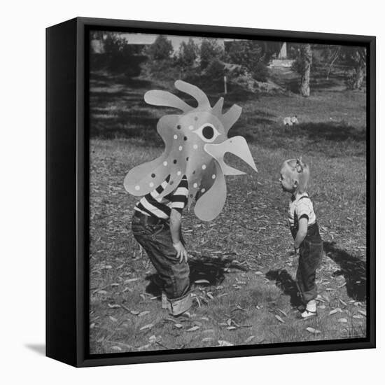 Curious Girl Looking at a Toy Chicken Head Toy by Charles Eames-Allan Grant-Framed Premier Image Canvas