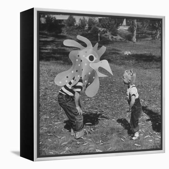 Curious Girl Looking at a Toy Chicken Head Toy by Charles Eames-Allan Grant-Framed Premier Image Canvas