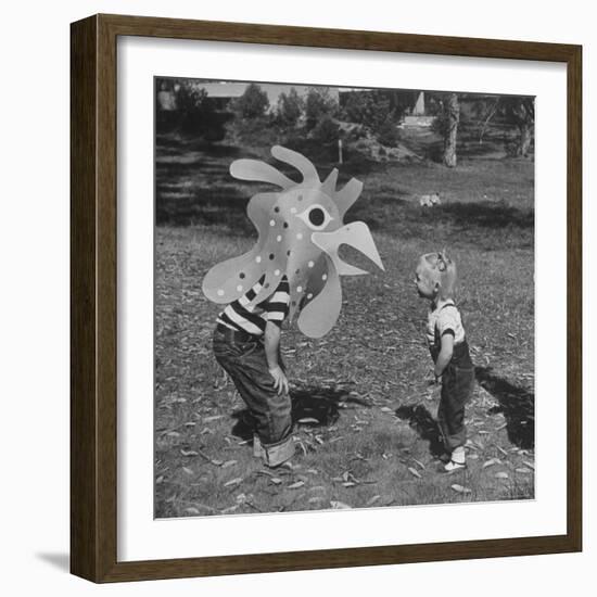 Curious Girl Looking at a Toy Chicken Head Toy by Charles Eames-Allan Grant-Framed Photographic Print