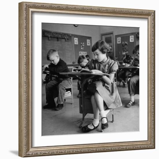 Cute Little Girl Busily at Work, Sitting in a Desk Chair in a Schoolroom, Other Pupils at Work Too-Gordon Parks-Framed Photographic Print