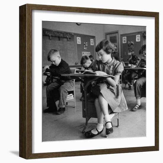 Cute Little Girl Busily at Work, Sitting in a Desk Chair in a Schoolroom, Other Pupils at Work Too-Gordon Parks-Framed Photographic Print