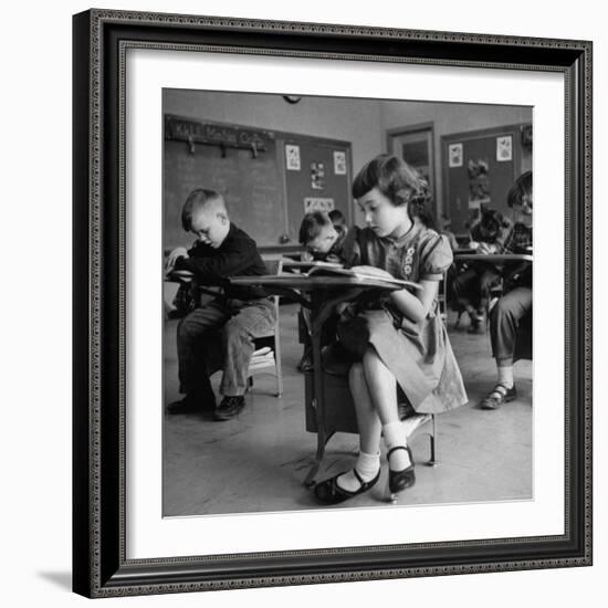 Cute Little Girl Busily at Work, Sitting in a Desk Chair in a Schoolroom, Other Pupils at Work Too-Gordon Parks-Framed Photographic Print