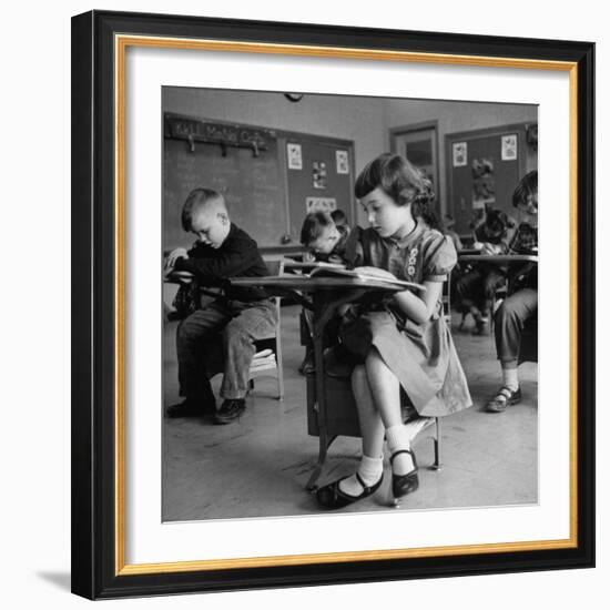 Cute Little Girl Busily at Work, Sitting in a Desk Chair in a Schoolroom, Other Pupils at Work Too-Gordon Parks-Framed Photographic Print