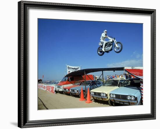 Daredevil Motorcyclist Evil Knievel in Mid Jump over a Row of Cars-Ralph Crane-Framed Premium Photographic Print