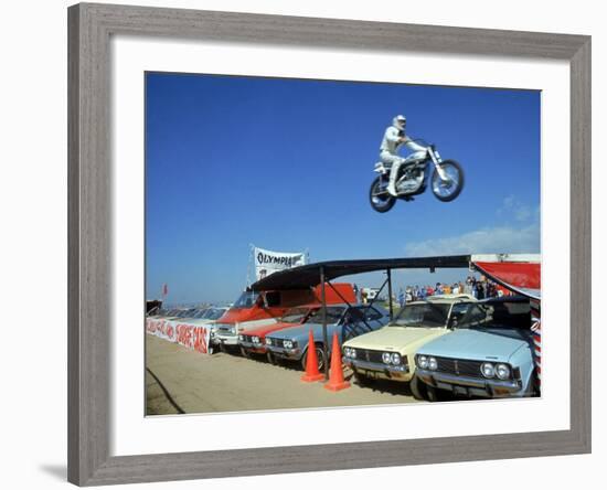 Daredevil Motorcyclist Evil Knievel in Mid Jump over a Row of Cars-Ralph Crane-Framed Premium Photographic Print