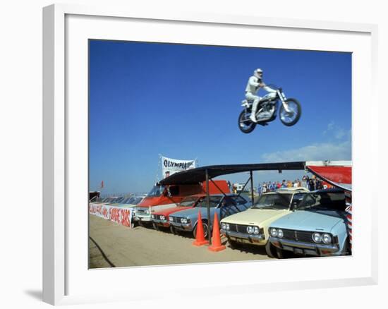 Daredevil Motorcyclist Evil Knievel in Mid Jump over a Row of Cars-Ralph Crane-Framed Premium Photographic Print