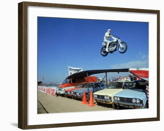 Daredevil Motorcyclist Evil Knievel in Mid Jump over a Row of Cars-Ralph Crane-Framed Premium Photographic Print