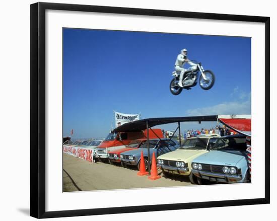 Daredevil Motorcyclist Evil Knievel in Mid Jump over a Row of Cars-Ralph Crane-Framed Premium Photographic Print