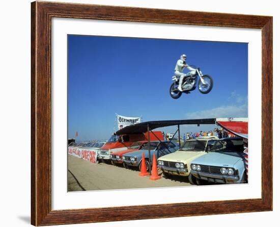 Daredevil Motorcyclist Evil Knievel in Mid Jump over a Row of Cars-Ralph Crane-Framed Premium Photographic Print