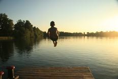 Boy Jumping into a Lake from a Dock at Sunset in the Summer-David Polite-Photographic Print