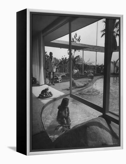 Designer Raymond Loewy Relaxing by Swimming Pool Which Runs from Outdoors Into Living Room-Peter Stackpole-Framed Premier Image Canvas