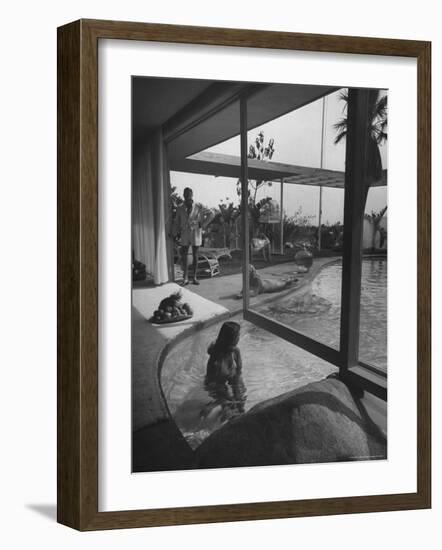 Designer Raymond Loewy Relaxing by Swimming Pool Which Runs from Outdoors Into Living Room-Peter Stackpole-Framed Premium Photographic Print