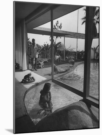 Designer Raymond Loewy Relaxing by Swimming Pool Which Runs from Outdoors Into Living Room-Peter Stackpole-Mounted Premium Photographic Print