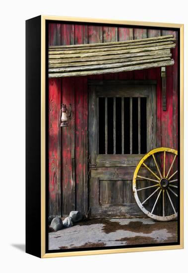 Detail of Old Wagon Wheel next to a Wooden Wild West Typical House-ccaetano-Framed Premier Image Canvas