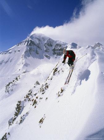 Downhill Skier Launching Off A Cornice In Front Of Lone Mountain