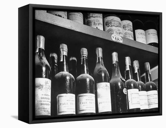 Dust-Covered Wine and Brandy Bottles Standing on Racks in a Wine Cellar-null-Framed Premier Image Canvas