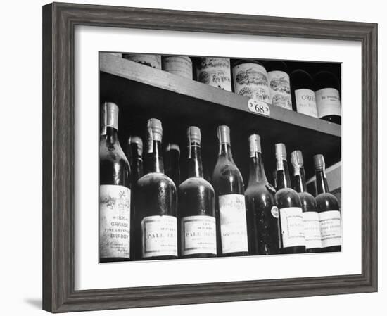 Dust-Covered Wine and Brandy Bottles Standing on Racks in a Wine Cellar-null-Framed Photographic Print