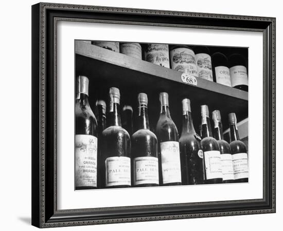 Dust-Covered Wine and Brandy Bottles Standing on Racks in a Wine Cellar-null-Framed Photographic Print