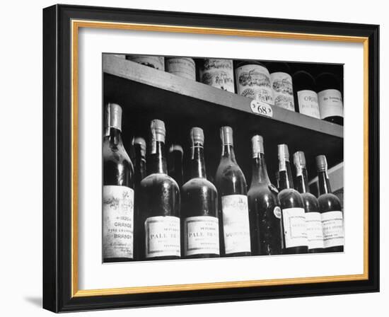 Dust-Covered Wine and Brandy Bottles Standing on Racks in a Wine Cellar-null-Framed Photographic Print