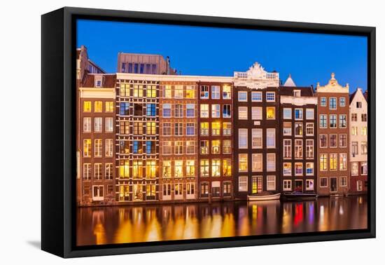 Dutch gables on row of typical Amsterdam houses at night with reflections in the Damrak canal-Neale Clark-Framed Premier Image Canvas