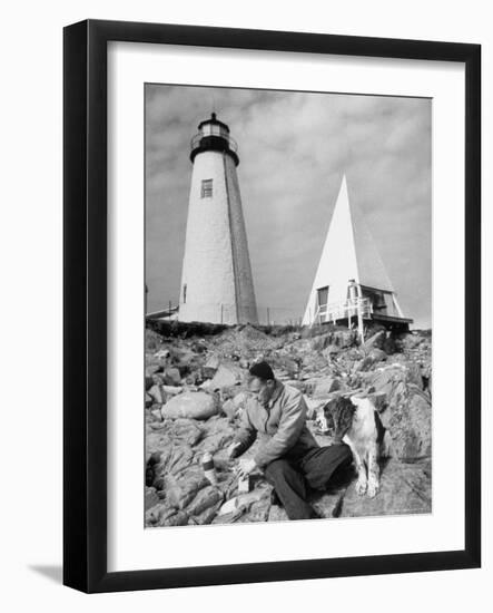Eddie Frank Preparing to Eat Lunch on Rocks Next to His Dog in Front of Lighthouse-Alfred Eisenstaedt-Framed Photographic Print