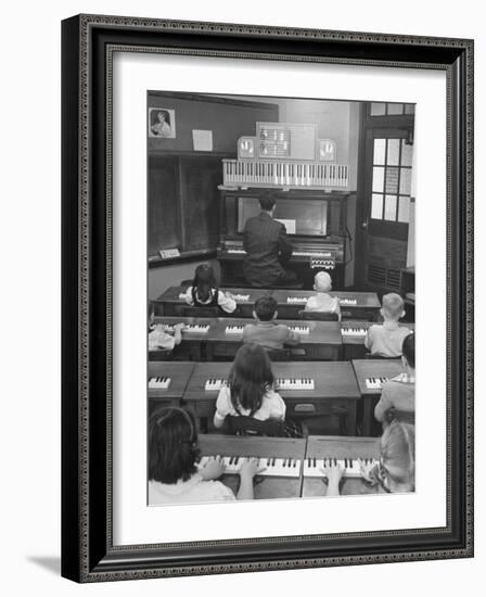 Elementary School Music Teacher Playing F-Major Chord on Piano, Keys Light up on Plastic Keyboard-Yale Joel-Framed Photographic Print