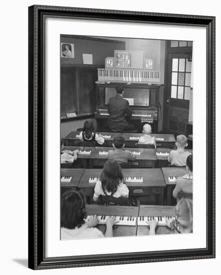 Elementary School Music Teacher Playing F-Major Chord on Piano, Keys Light up on Plastic Keyboard-Yale Joel-Framed Photographic Print