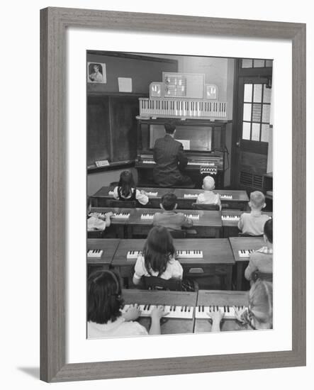 Elementary School Music Teacher Playing F-Major Chord on Piano, Keys Light up on Plastic Keyboard-Yale Joel-Framed Photographic Print