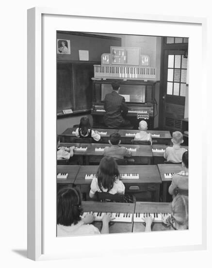 Elementary School Music Teacher Playing F-Major Chord on Piano, Keys Light up on Plastic Keyboard-Yale Joel-Framed Photographic Print