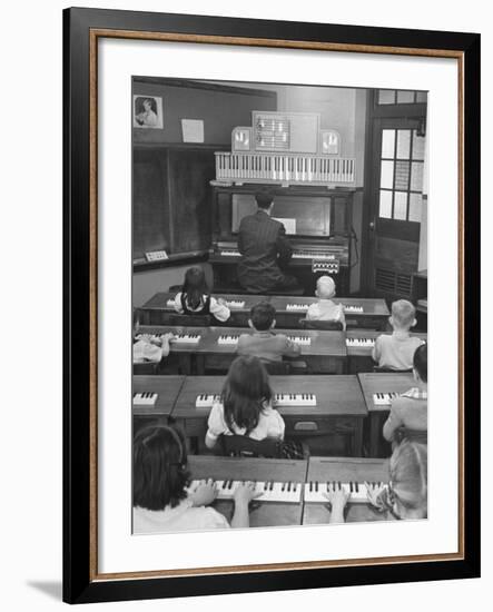 Elementary School Music Teacher Playing F-Major Chord on Piano, Keys Light up on Plastic Keyboard-Yale Joel-Framed Photographic Print