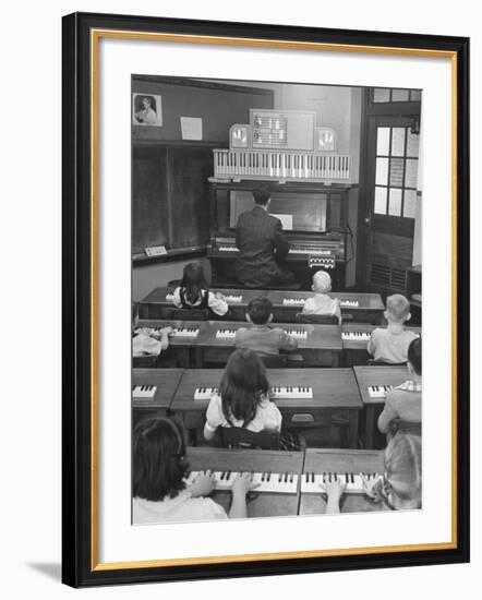 Elementary School Music Teacher Playing F-Major Chord on Piano, Keys Light up on Plastic Keyboard-Yale Joel-Framed Photographic Print