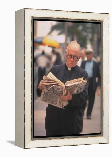 Episcopalian Priest Reading a Newspaper While Walking in Street, New York City-Vernon Merritt III-Framed Premier Image Canvas