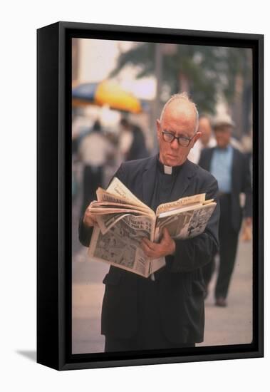 Episcopalian Priest Reading a Newspaper While Walking in Street, New York City-Vernon Merritt III-Framed Premier Image Canvas