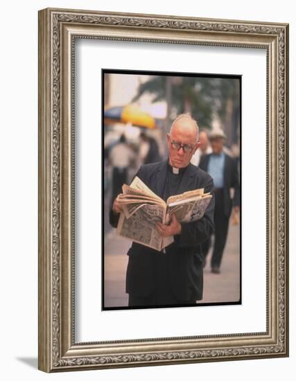 Episcopalian Priest Reading a Newspaper While Walking in Street, New York City-Vernon Merritt III-Framed Photographic Print