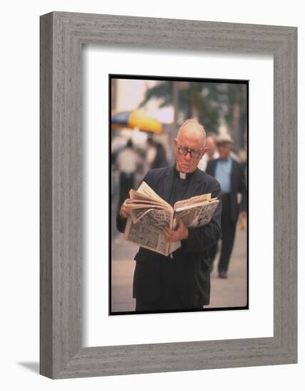 Episcopalian Priest Reading a Newspaper While Walking in Street, New York City-Vernon Merritt III-Framed Photographic Print