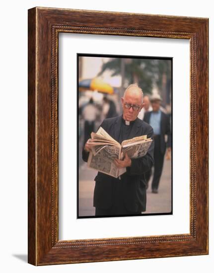 Episcopalian Priest Reading a Newspaper While Walking in Street, New York City-Vernon Merritt III-Framed Photographic Print