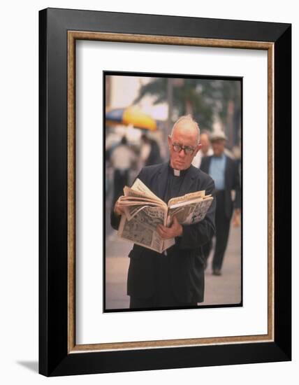 Episcopalian Priest Reading a Newspaper While Walking in Street, New York City-Vernon Merritt III-Framed Photographic Print