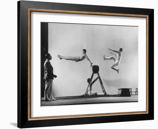 Erik Flensted Jensen, Coach of Danish Gymnastic Team, Watching as Three Men Perform-Gjon Mili-Framed Photographic Print