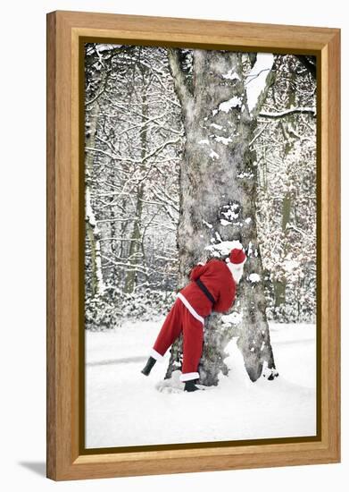 Father Christmas in Snow Behind Tree-null-Framed Premier Image Canvas