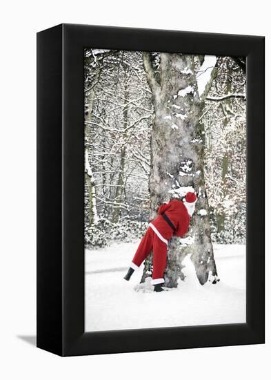 Father Christmas in Snow Behind Tree-null-Framed Premier Image Canvas