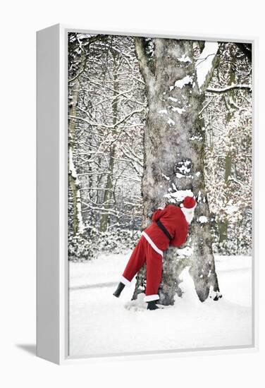 Father Christmas in Snow Behind Tree-null-Framed Premier Image Canvas