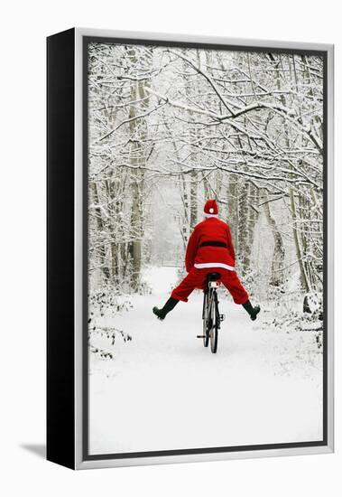 Father Christmas Riding Bicycle in Snowy Woodland Path-null-Framed Premier Image Canvas