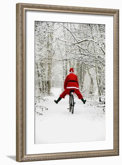 Father Christmas Riding Bicycle in Snowy Woodland Path-null-Framed Photographic Print