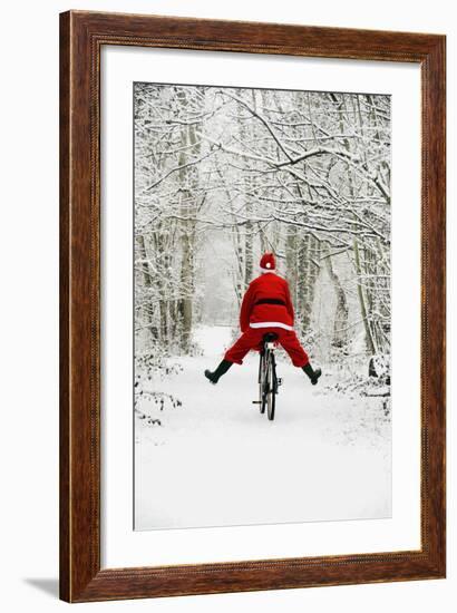 Father Christmas Riding Bicycle in Snowy Woodland Path-null-Framed Photographic Print