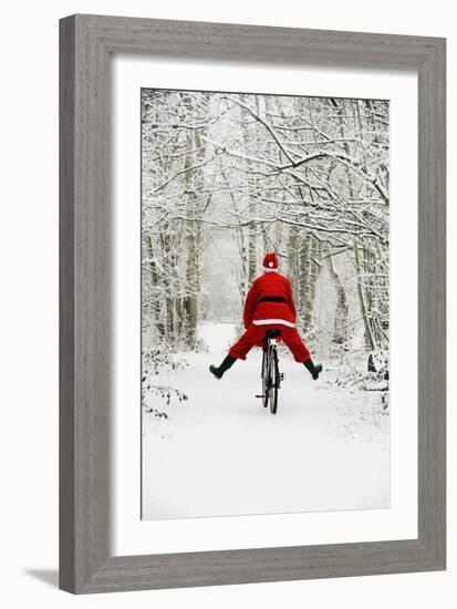 Father Christmas Riding Bicycle in Snowy Woodland Path-null-Framed Photographic Print