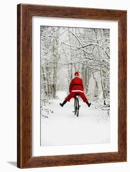 Father Christmas Riding Bicycle in Snowy Woodland Path-null-Framed Photographic Print