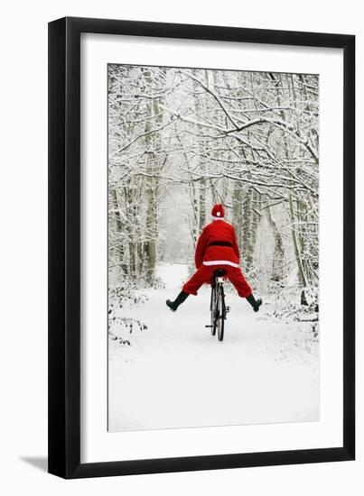 Father Christmas Riding Bicycle in Snowy Woodland Path-null-Framed Photographic Print