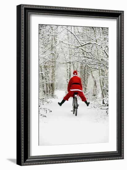 Father Christmas Riding Bicycle in Snowy Woodland Path-null-Framed Photographic Print