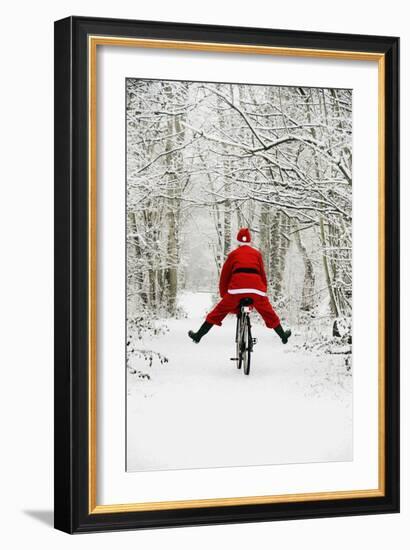 Father Christmas Riding Bicycle in Snowy Woodland Path-null-Framed Photographic Print